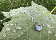 Load image into Gallery viewer, Silver petaled translucent opal-like white flower, with tiny pearl. On a dainty ball chain. Photographed on the back of a raindrop covered leaf.

